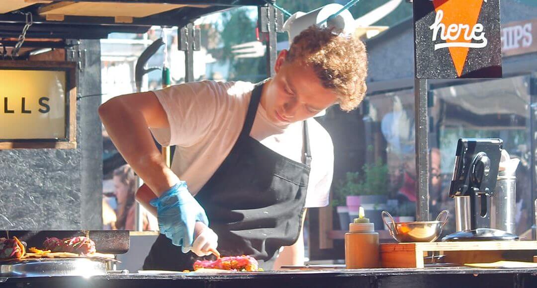 6 Lessons I Learned Setting Up a Street Food Stall image - young male chef creating a hotdog in a popup food stall