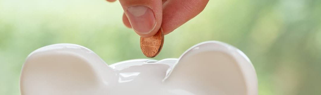 Close up of a coin being inserted into a saving piggy bank