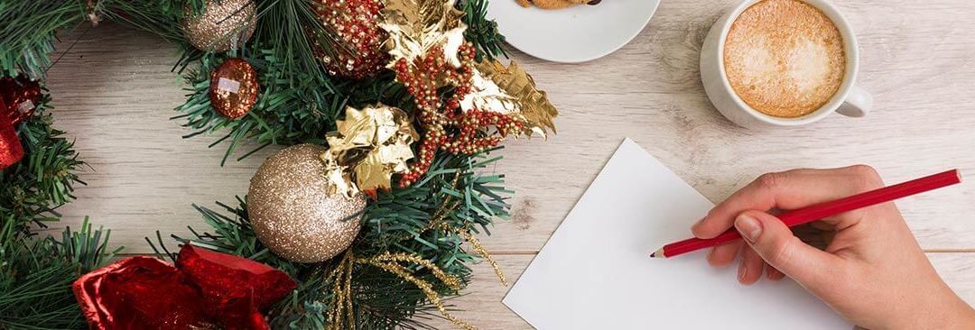 Christmas Marketing Ideas for Small Businesses 2017 - person making notes with pen and paper on a tabletop with Christmas wreath