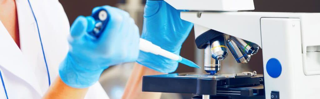 DNA of an Entrepreneur - image - researches in gloves placing pipette into microscope samples