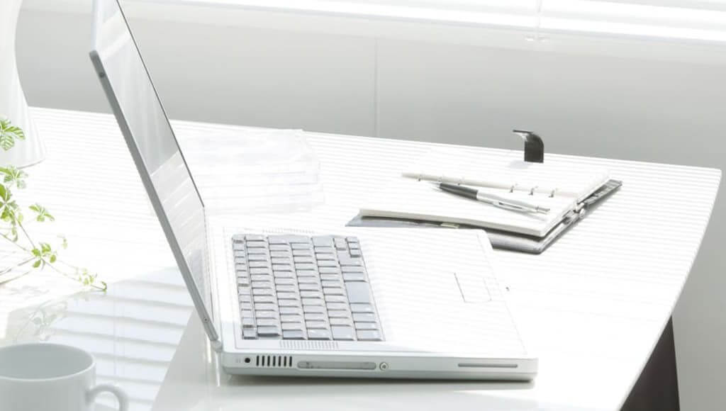 How To Create A Green Workplace In 6 Steps image - white top desk with laptop and leafy creeping plant