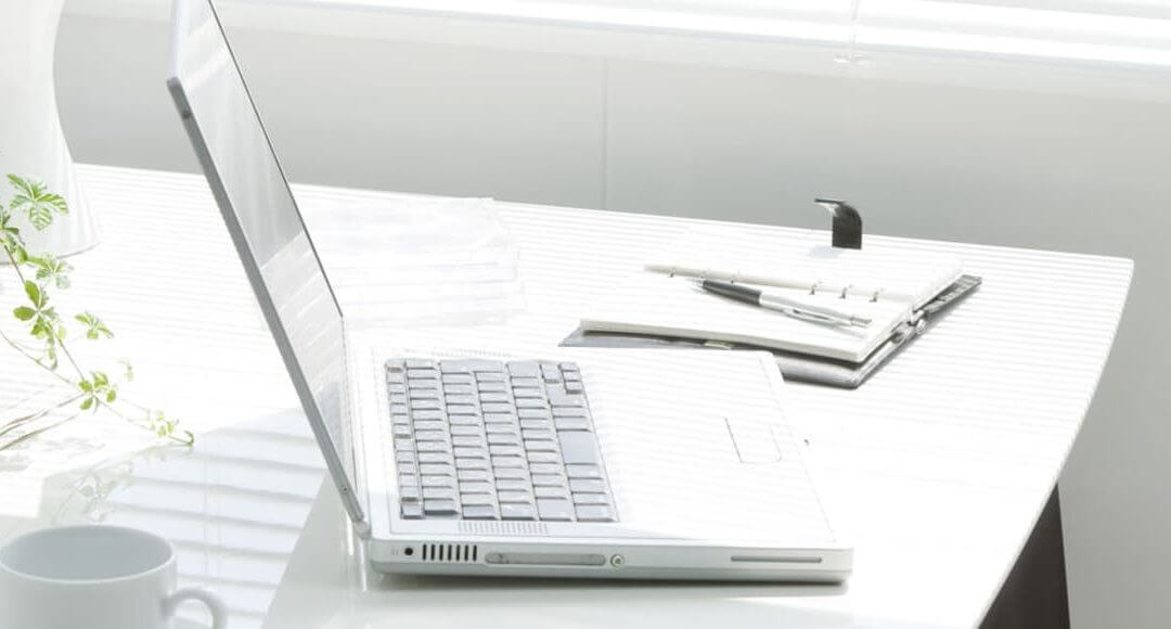 How To Create A Green Workplace In 6 Steps image - white top desk with laptop and leafy creeping plant