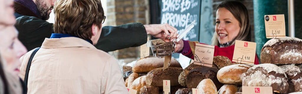 Small female business owner at a market stall selling bread