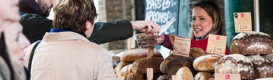 Small female business owner at a market stall selling bread