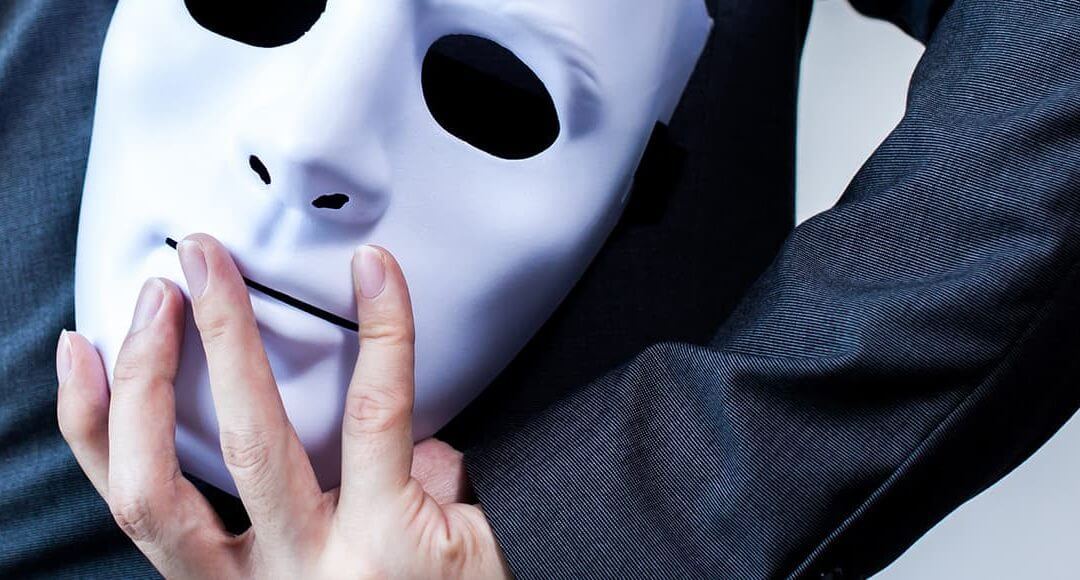 Understanding Identity Fraud: How to Protect your Company Directors image - man wearing dark clothing hiding a white mask behind his back