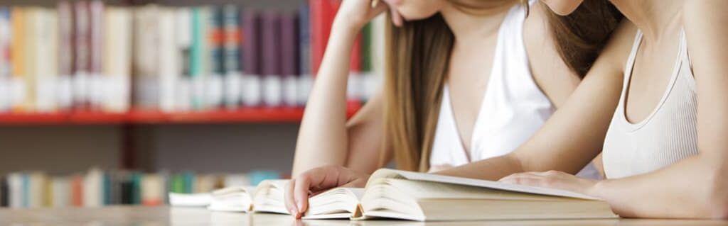 two female students researching business ideas in a library