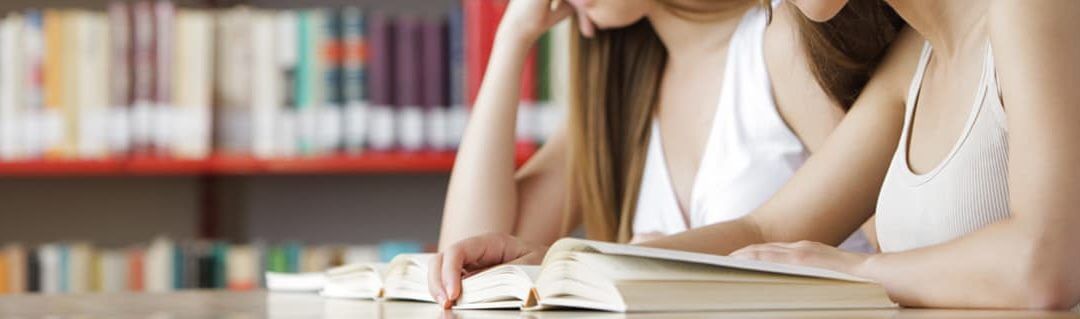 two female students researching business ideas in a library