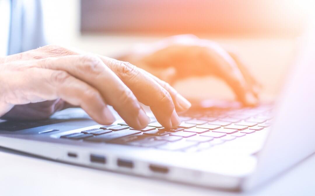 Image - hands typing on laptop, with a sun glare overlay