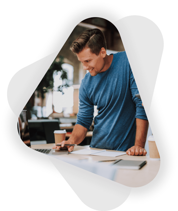 young male entrepreneur stands working on a laptop